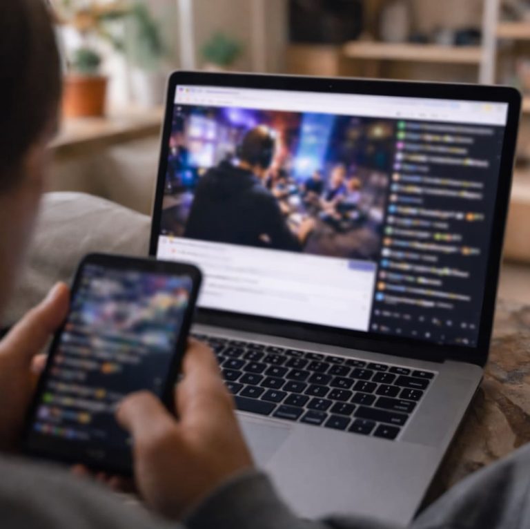 Någon som sitter tyst och tittar på en Twitch-sändning på en laptop, där chatten rullar snabbt förbi i lätt oskärpa medan innehållet på skärmen observeras utan att delta