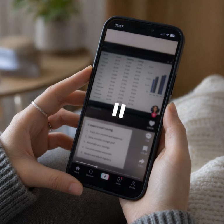 Närbild av en pausad mobilvideo där skärmen är lätt suddig och händerna håller telefonen som om tittaren försöker hinna läsa allt